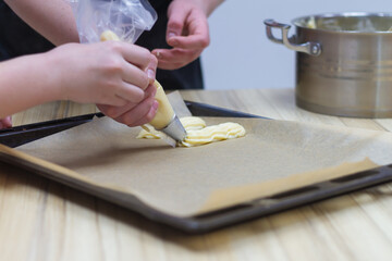 Squeeze the dough out of the pastry bag onto a baking tray for baking eclairs