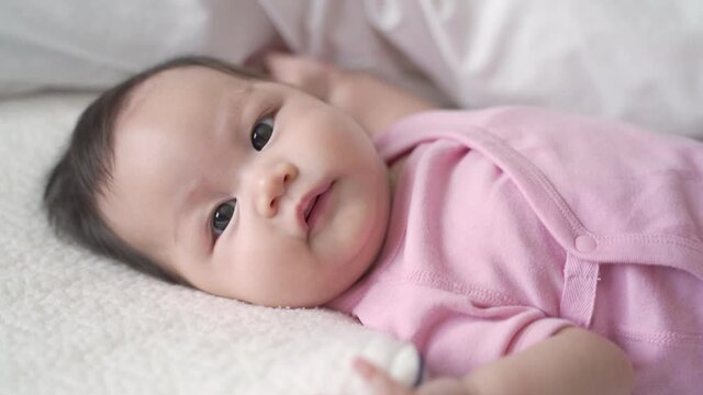 asian baby infant laying down on white soft bed happy and smile. 3 months old baby facial expression. 