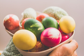 Fototapeta na wymiar Holy Week Concept - Hands Holding Bowl with Colorful Easter Eggs 