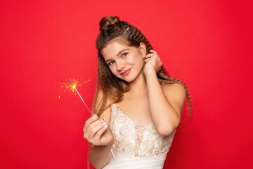 pyrotechnics and people concept - smiling young woman or teenage girl happy woman with sparklers celebrate in white dress on red background.