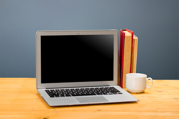 Fototapeta na wymiar Laptop with blank screen, cup of coffee and books or notebooks on a wooden table. mockup for your text