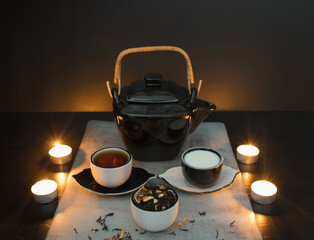 Beautiful black and white tea ceremony set: teapot and small cups with tea and milk and saucers...