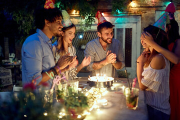 Group of cheerful friends surprising a female celebrant at the open air birthday party. Quality friendship time together