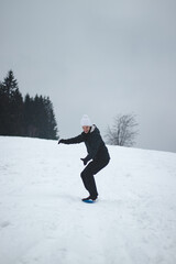 sixteen-year-old boy learns to keep his balance on a plastic snowboard and drive down a few meters down the piste. Winter sports. A smile on his face at repeated attempts