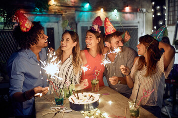 Group of friends playing with sprinklers at the open air birthday party. Quality friendship time together