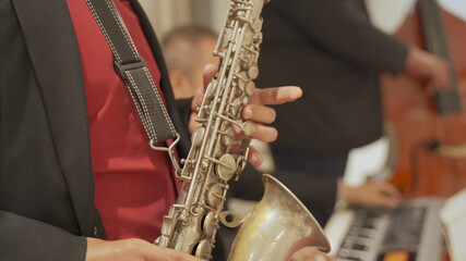close up asian Saxophonist playing a saxophone on stage performance.