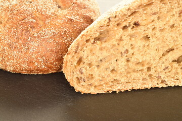 Two fresh halves of a loaf of bread on a slate board, close-up.