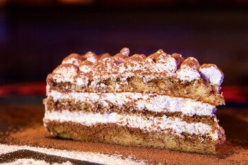Slice of self-made italian tiramisu dessert served on a plate. Close-up, selective focus.