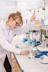 Fototapeta premium A laboratory assistant pours reagents into a flask using a special astomatic pipette. Assistant in the chemistry laboratory at the university