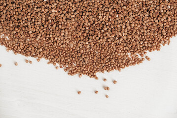 Buckwheat is randomly scattered on a white background. Top view. Copy, empty space for text