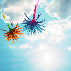 Abstract bright multicolored palms on a background of blue sky with clouds.