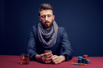 Stylish bearded Man playing in dark casino, smoking cigar, drink whiskey