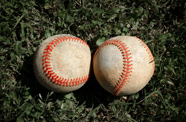Two worn old baseball in the grass