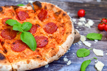 Home made italian  pepperoni   pizza with  tomatoes, mozzarella and parmesan cheese and fresh basil 