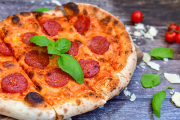 Home made italian  pepperoni   pizza with  tomatoes, mozzarella and parmesan cheese and fresh basil 