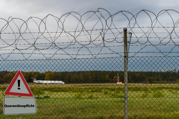 Schild Quarantänepflicht vor Flugzeug