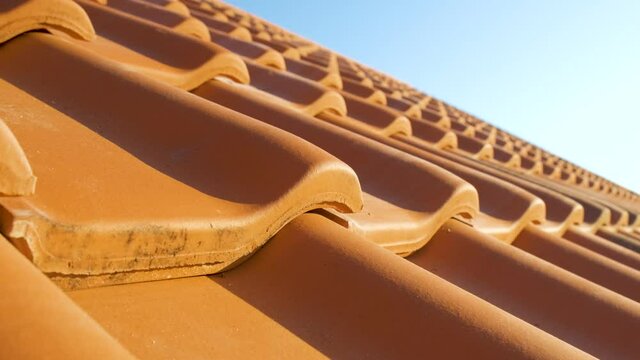 Overlapping rows of yellow ceramic roofing tiles covering residential building roof.