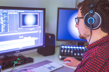 Video editor in the cutting room, close up, monitors in blurry background