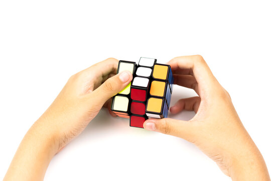 SAMUT-SAKHON, THAILAND - APRIL 02, 2021 : Hands of a young girl trying to solve the Rubik's Cube puzzle.