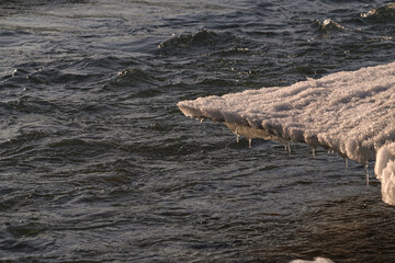 Melting ice floe on the edge of the river bank. 