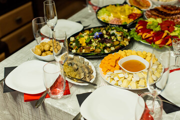 Glasses goblets on white table. Room with table serving fruits and dishes and meal. cheese, honey, salads, snacks.