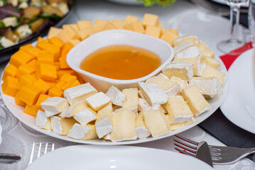 Glasses goblets on white table. Room with table serving fruits and dishes and meal. cheese, honey, salads, snacks.