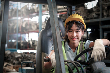 Industrial worker woman wearing helmet driving forklift car at manufacturing plant factory...