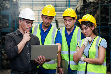 Industrial engineer worker woman and man wearing helmet discussing and working together with laptop computor at manufacturing plant factory, young people working in industry