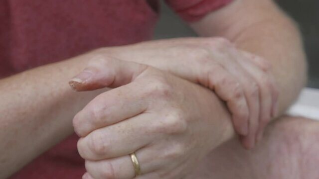 Adult hands slowly rubbing together over cracked and blistered skin, close up