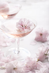 Romantic still life with rose wine  in the two  rare coupes champagne glasses with beautiful soft flowers, selective focus.  Summer drink concept