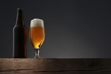 Glass and bottle of beer on dark grey background