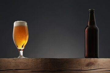 Glass and bottle of beer on dark grey background