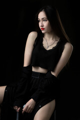 A beautiful young girl with long hair in black short clothes on a dark background.