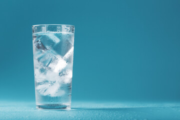 Ice cubes in a glass with crystal clear water on a blue background. - Powered by Adobe