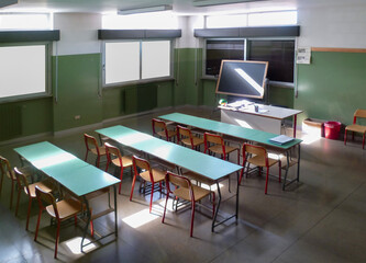 primary school, empty classroom in daylight, blind blackboard and deserted desks
