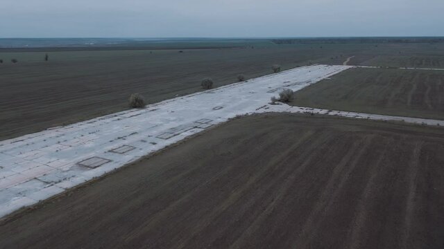 Drone fly above old runway strip on lost military airfield on the endless steppen fields at autumn