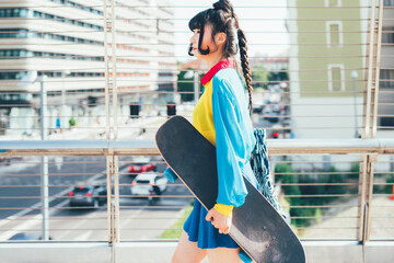 Young diverse asian woman walking outdoor in the city holding skateboard