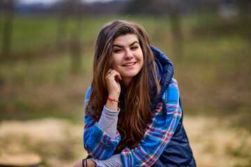 portrait of a young woman wearing a hooded jacket with nature in the background