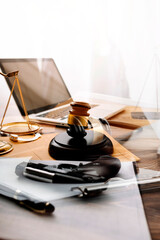 Justice and law concept.Male judge in a courtroom with the gavel, working with, computer and docking keyboard, eyeglasses, on table in morning light