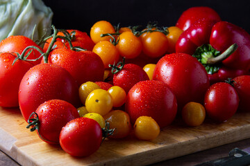 Vegetables: red and yellow tomatoes, bell peppers and cabbage on a wooden board
