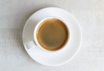 Fragrant espresso in a white cup and saucer. Morning tradition. Home coffee making concept. Horizontal orientation. Top view.