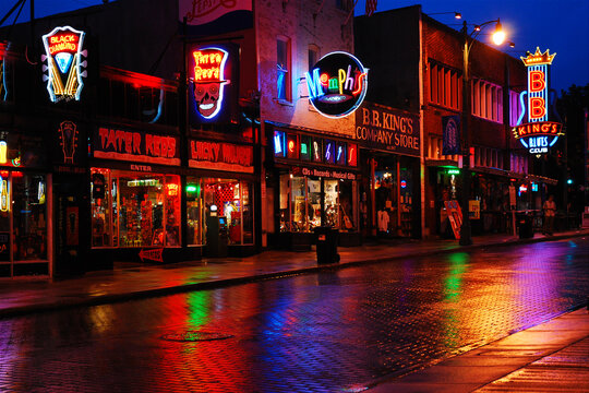 The neon lights form the bars and cafes of Beale Street in Memphis are reflected in the rainy street at night