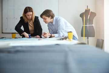 Fashion expert teaching trainee on proper cutting of fabric