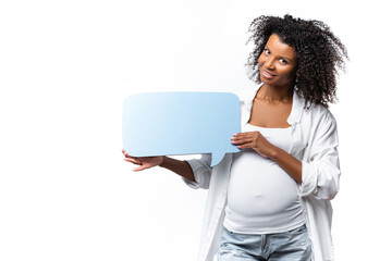 Smiling african american pregnant woman holding speech bubble isolated on white