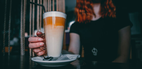 Female hands hold a glass of flat white coffee in caffee