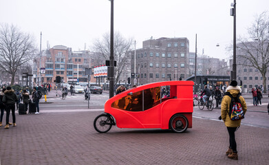 Obraz premium On the sidewalk original red bicycle rides. Citizens are walking and riding bicycles