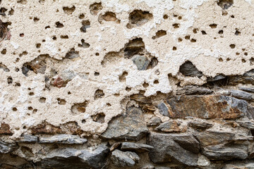 Old damaged dirty wall with cracks and wholes. Ruin facade made of natural stone and Bricks. A vintage background for design