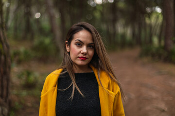 Woman in a yellow coat and hat in hand. Casual fashion.