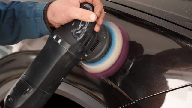 Black car body polishing with polisher tool in auto service