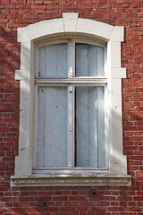 Altes Fenster in einem Haus aus roten Ziegelsteinen.